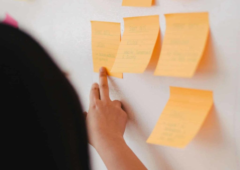 Woman using post it notes on a board to prioritise workload.