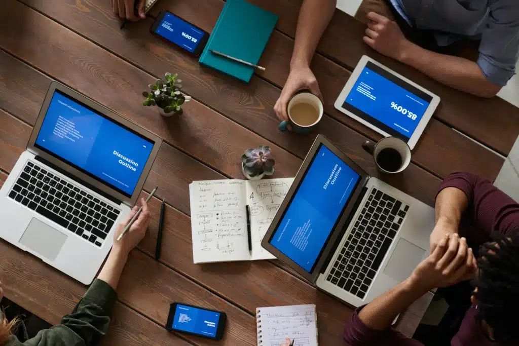 Top view of professional at a a table discussing meeting notes on laptops.