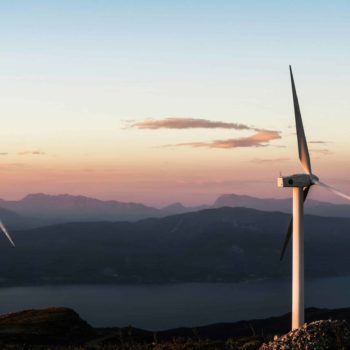 Wind turbines on top of a hilly landscape at sunrise. ISO Net Zero Standard. Sustainit