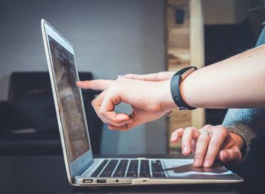 Hands pointing at a laptop screen