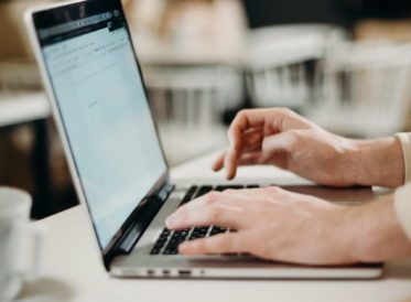 Hands typing on a laptop at a desk.