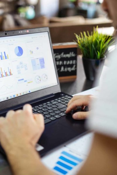 Man working on a laptop showing data visualizations as graphs.