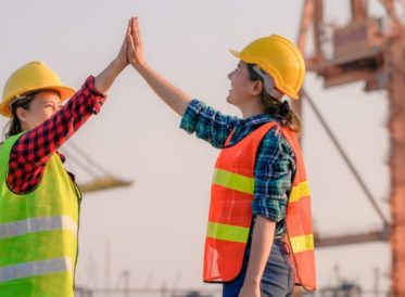Two construction workers high fiving on site